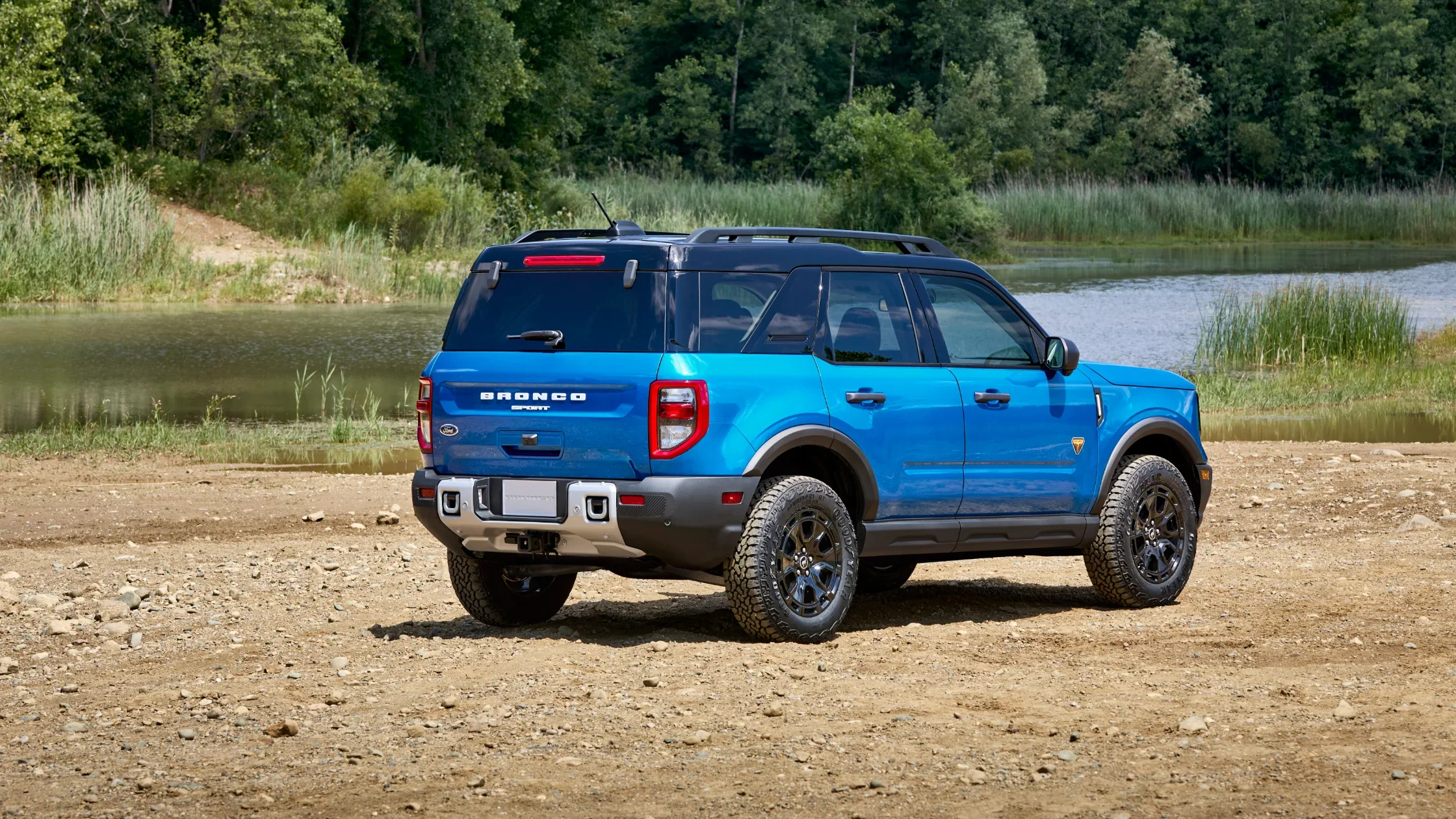 Rear view of a blue 2025 Ford Bronco® Sport parked near a lake on rugged terrain
