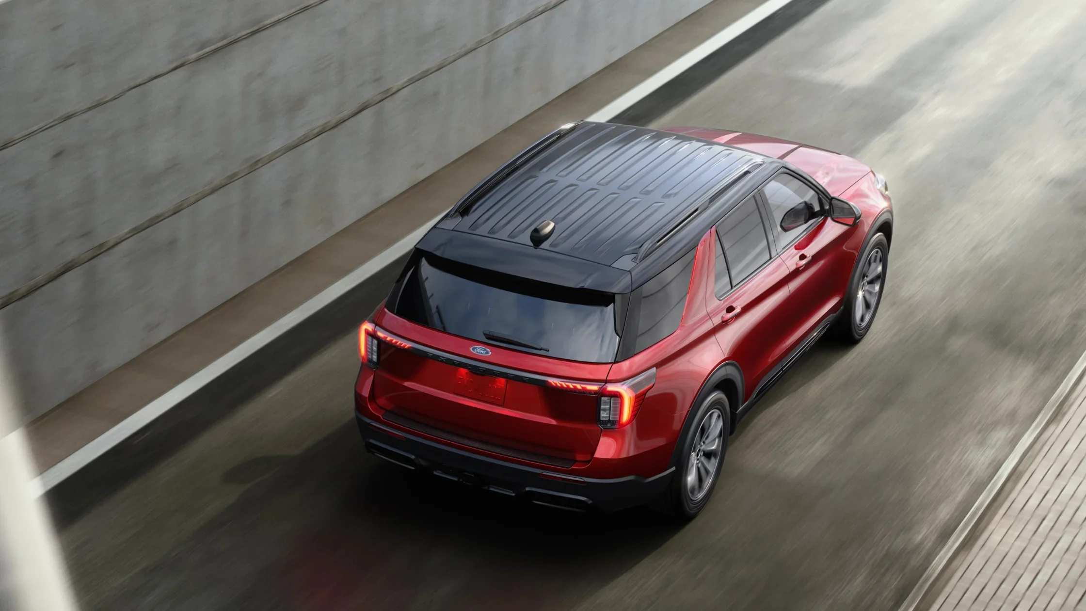 Rear three-quarter view of red and black 2025 Ford Explorer driving through a tunnel.