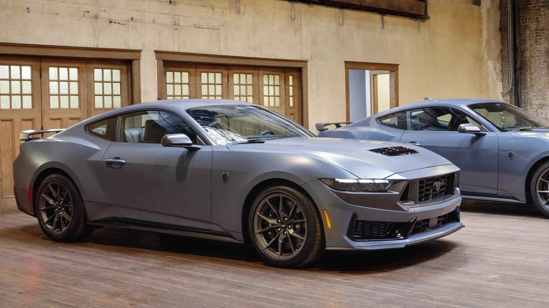 2025 Ford Mustang® in matte gray parked indoors showcasing aggressive front fascia and performance wheels.