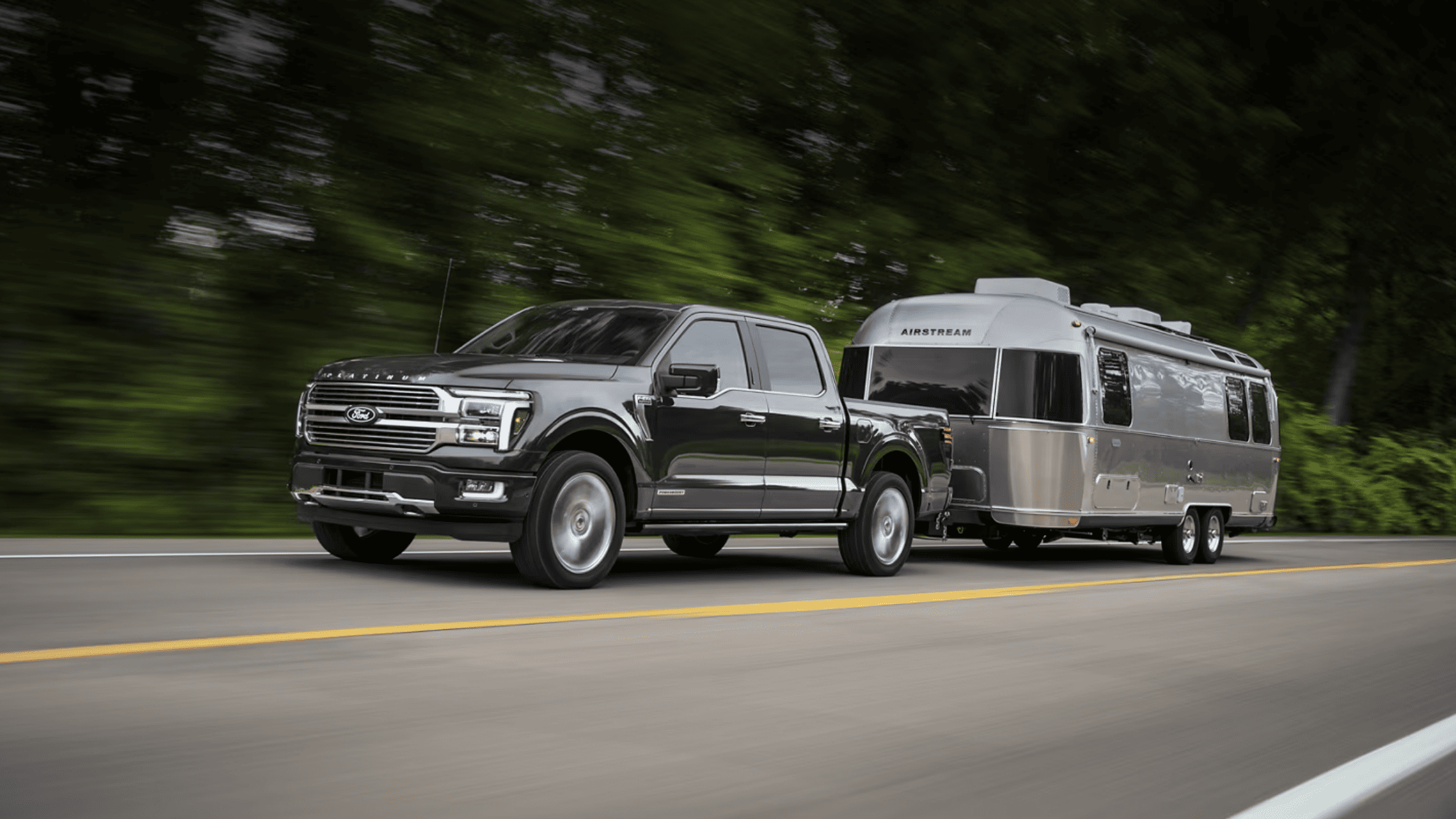 2025 Ford F-150 towing Airstream trailer on highway surrounded by trees